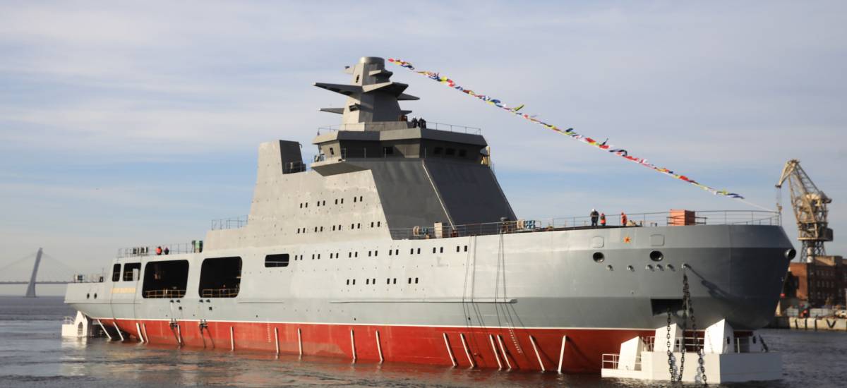 Le brise-glace militaire russe de la classe Ivan Papanine est amarré dans un port, arborant une coque grise et rouge, décoré de pavillons de signalisation maritimes.